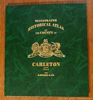 Front hardcover showing dark green cover with gold embossed text and heraldic emblem