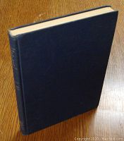 Dark blue hardcover book standing on a wooden surface.