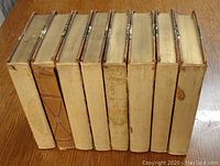 Eight hardcover volumes showing wear, missing spine strips, and marbled boards with leather corners and spines.