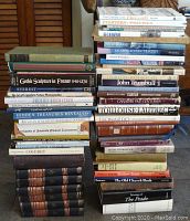 Photo of various stacked art and coffee table books showing diverse titles and conditions