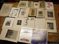 Overview of various antique prints including black and white portraits, technical drawings, and colored maps spread on table