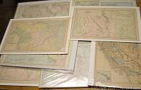 Photo showing a group of antique map prints stacked, including maps of Canada and surrounding regions, shrink wrapped or bagged on backing boards.