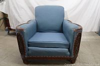 Front view of blue upholstered parlor chair with removable seat cushion and carved wood frame.