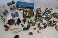 Wide shot showing layout of various porcelain village buildings, trees, and accessories including power strip box