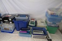 Photo showing a large collection of plastic bins, sorters, and organizers in different sizes and colors arranged on a table against a white backdrop.