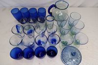 Wide shot of large collection of cobalt blue glassware including tumblers, goblets, a pitcher, and a covered dish.