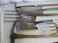 Photo showing the full lot of excavation tools arrayed, including shovels, pitchforks, a digging hoe, a pickaxe, and a garden fork, all laid out to display condition and variety.