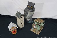 Photo showing all four items together on black cloth background: three bird houses and one owl figurine.
