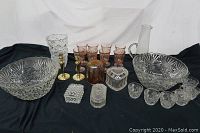 Full lot of decorative glass including bowls, stemware, trinket boxes, small cups, and a pitcher on black cloth