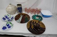 Full lot of decorative glassware, pottery vases, plates, platters, and glasses arranged on a white cloth