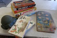 Vintage board games stacked with a plastic helmet toy on the table, Operation Moon Probe game visible.