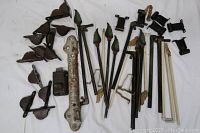 Top view of assorted antique window hardware laid out on a white surface, including pulleys, rods, decorative tie backs, brackets, and a latch.