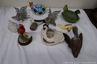 Full view of bird and figurine collection on white cloth background showing all nine pieces.