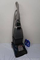 Front view of Hoover upright carpet cleaning machine with two blue bottles of cleaner beside it