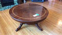 Full view of the round wooden coffee table showing the entire tabletop and legs on hardwood floor.
