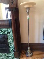 Full view of the lamp standing beside fireplace trim showing overall height and base