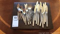 Decorative and plain stainless steel flatware pieces arranged on wood board