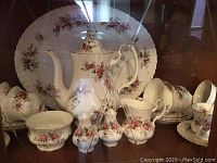 Full set displayed including coffee pot, serving platter, creamer, sugar bowl, cups, and saucers