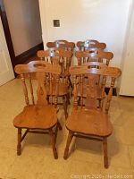 Front and back view of six matching solid wood kitchen chairs arranged in two rows.