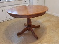 Full view of round wood pedestal table with smooth finish on top.