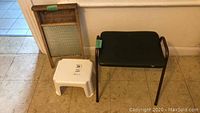 Photo showing the vintage wood-framed washboard, small white plastic step stool, and the 1950s metal-framed bench with vinyl seat arranged side by side on tile floor against wall