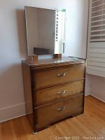 Front view of wood dresser with three drawers and rectangular mirror on top against wall.
