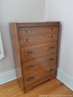 Front view of mid-century tallboy chest of drawers showing the wood grain finish and brass hardware on drawers.