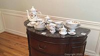 Full view of 32-piece Korosten porcelain tea and luncheon set displayed on dark marble buffet top showing cups, saucers, plates, serving bowl and pitcher.