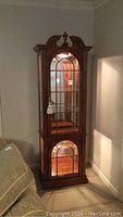 Full view of the wooden display cabinet with glass doors and internal lighting, showing its overall height and design.