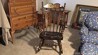 Full view of wooden rocking chair showing dark wood finish and surrounding furniture.