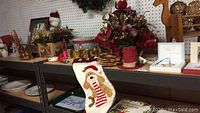 Overview of holiday decor items on shelves including faux flower arrangements, Santa stocking, holiday-themed dishes and figurines
