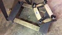 Small wooden dolly viewed from top angle showing four caster wheels and protective padding on top surface.