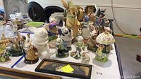 Collection of porcelain and stuffed rabbit figurines arranged on a table showing various poses and sizes.