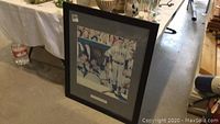 Framed Norman Rockwell print with Chicago Bears players, displayed leaning on floor.