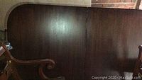 Photo showing the dark wood surface of the dining table's top including the detachable leaf portion.