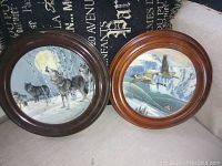 Two vintage round collector plates in wood frames, placed side by side. One plate with wolf artwork, one with ducks.