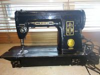 Front side view of the black Singer 301 sewing machine on a table, showing overall shape and Singer branding.