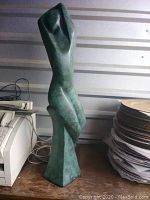 Front and side views showing the tall, green ceramic statue with abstract female form.