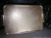 Full view of the large rectangular brass serving tray showing the patterned surface and handle on one side.