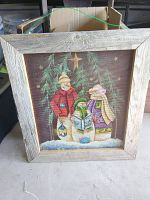 Front view of rustic Christmas painting on metal mesh with barnwood frame, showing three characters and hanging stars against a dark background.