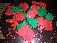 Top-down view of 20 vintage red and green Christmas-themed plastic cookie cutters arranged on a surface