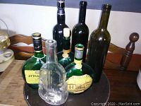 Seven vintage decorative bottles displayed on a table, including labeled Mateus and Armagnac bottles and a clear violin-shaped bottle.