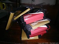 Stack of 10 pairs of men's dress socks with tags attached, mostly in black and dark gray colors, packaged with gold and red label tags.