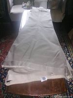 Photo showing two pairs of beige Dockers pants laid flat on a wooden table, highlighting the color and length of each pair.