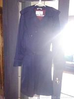 Front view of navy blue men's trench coat hanging on a hanger, displaying full length and belt.