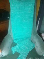 Green knit mermaid sheath blanket draped over a chair