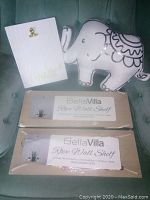Lot showing two BellaVilla rope wall shelves in packaging, a white clipboard labeled 'Canada', and an elephant pillow on a green upholstered chair.