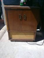 Full front view of the vintage wooden stereo cabinet with two doors and speaker grille.