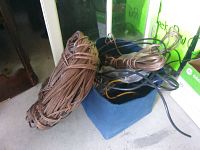 Large roll of brown transparent speaker wire coiled on floor next to blue container with miscellaneous wires partly visible inside