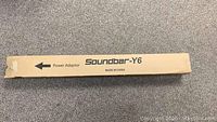Cardboard box with 'Soundbar-Y6 Power Adaptor' printed on it, indicating original packaging for the power adapter of the soundbar.